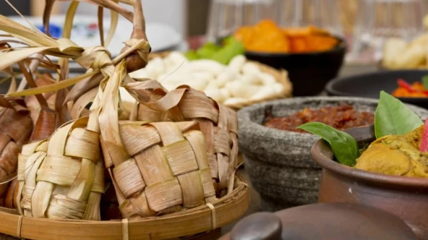 Sebuah meja makan Lebaran yang meriah dengan ketupat beras sebagai pusat perhatian, dikelilingi oleh hidangan 